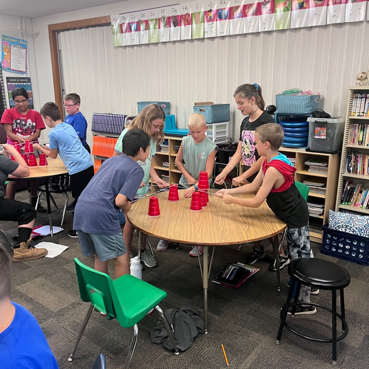 Webster 5th graders practicing working together by trying to accomplish the cup stacking challenge.