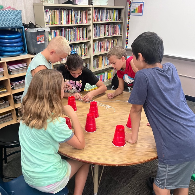 Webster 5th graders practicing working together by trying to accomplish the cup stacking challenge. 