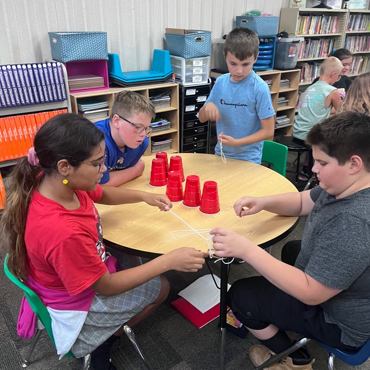Webster 5th graders practicing working together by trying to accomplish the cup stacking challenge. 