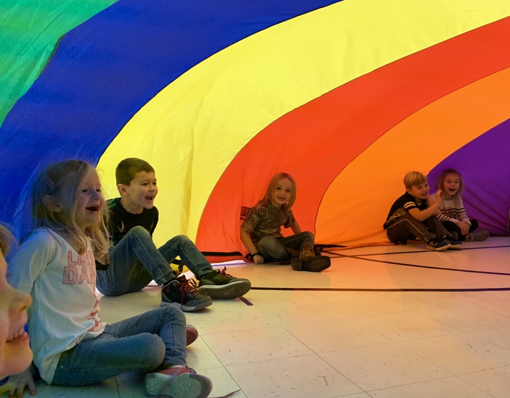 Students sitting under a parachute igloo.